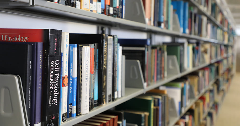 Books on shelves in a library with a focus on scientific research