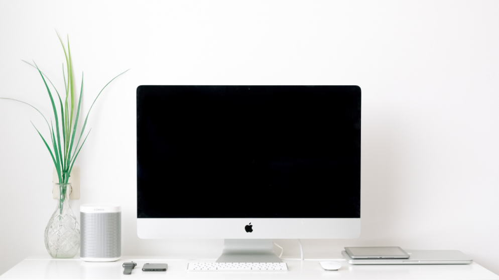 A Mac sitting on top of a white desk.